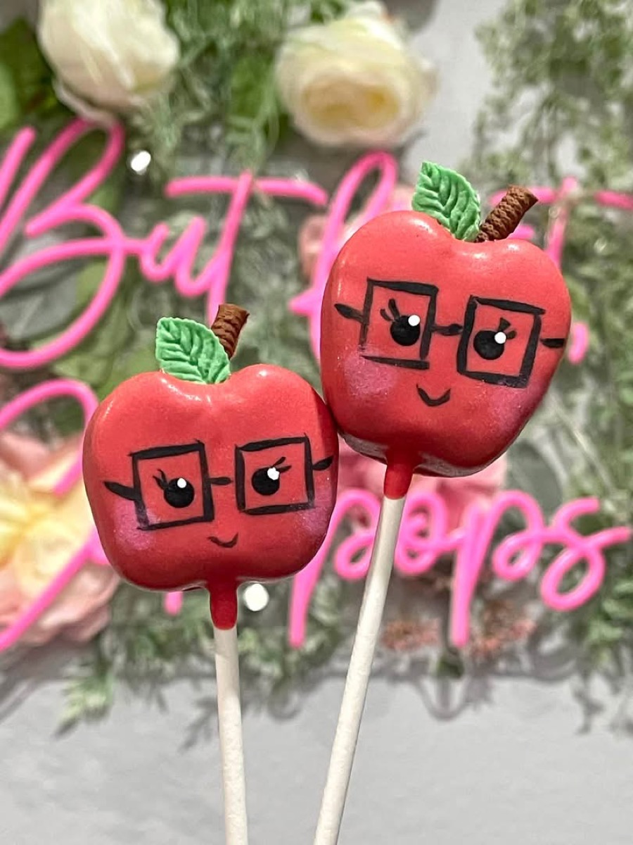 Red apple cake pops with hand-drawn glasses and a smile