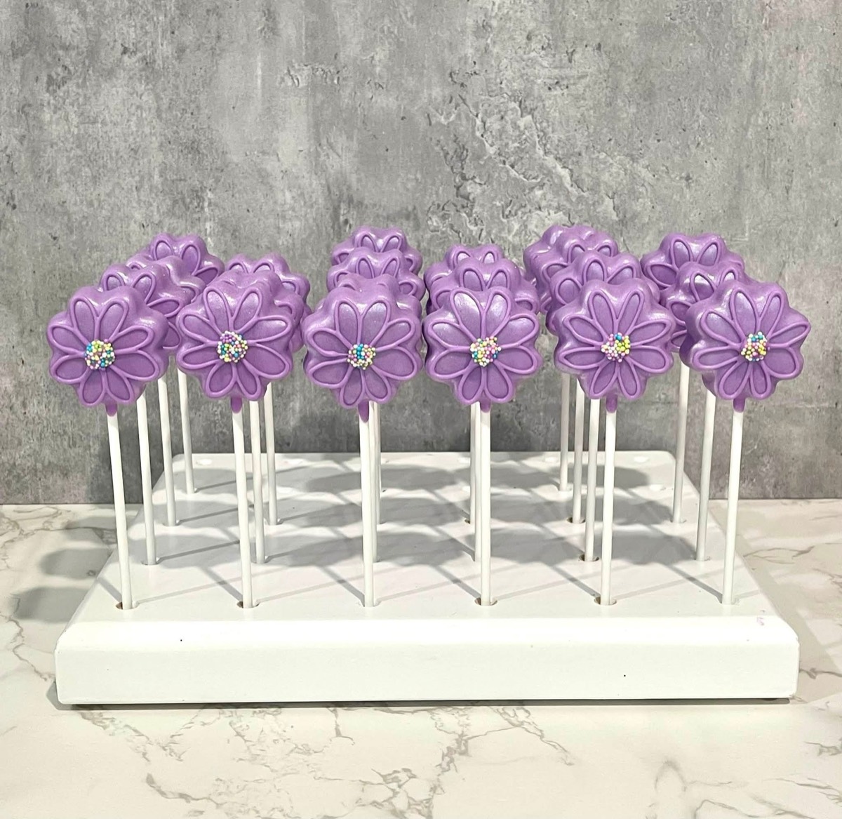 Lavender flower cake pops on a white display stand