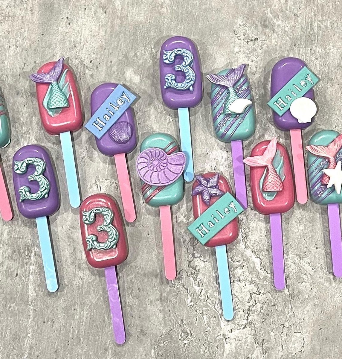 Mermaid-theme cakesicles with tails, shells and a number 3
