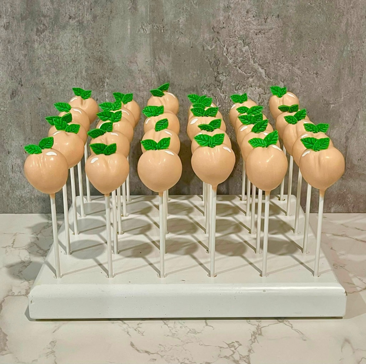 A full rack of peach cake pops with green leaves