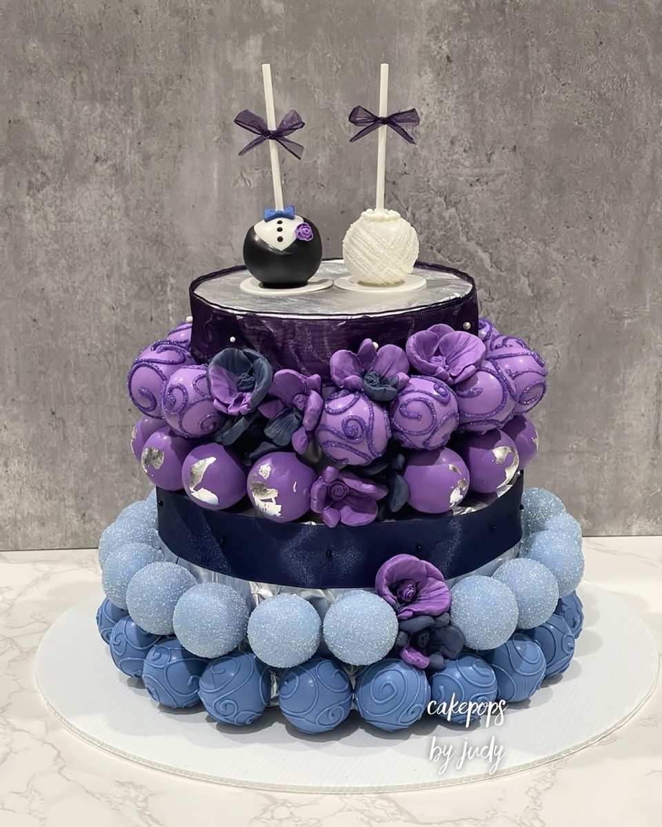 Two-tier cake pop tower in purple and blue with silver leaf and sugar flowers
